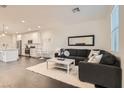 Bright living room with a cozy dark sectional sofa, white rug, and open floor plan at 690 Last Dance Pl, Henderson, NV 89011