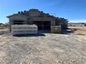 Exterior of an unfinished home featuring a three-car garage with a gravel yard, under a clear blue sky at 1831 E Deerskin St, Pahrump, NV 89048