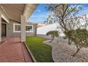 Relaxing side yard featuring artificial grass, decorative rock, and mature trees at 2108 Plaza Del Dios, Las Vegas, NV 89102