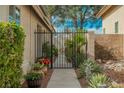 Metal garden gate with lush landscaping of green bushes, various plants and red flowers at 3213 Oyster Bay St, Las Vegas, NV 89117