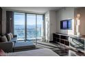 Well-lit living room featuring mountain views, a comfortable gray sofa, and wall-mounted television at 4381 W Flamingo Rd # 3303, Las Vegas, NV 89103