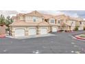 Exterior view of tan townhomes featuring multiple garages with white doors and terra cotta roofing at 5855 Valley Dr # 2018, North Las Vegas, NV 89031