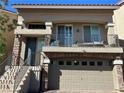 Inviting exterior showcasing a balcony and a two-car garage with brick accents at 8113 Mineola Palms St, Las Vegas, NV 89139