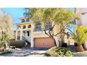 Two-story home with tan stucco, brick driveway, mature trees, and an attached two-car garage at 10716 Shasta Glow Ct, Henderson, NV 89052