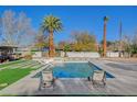 Inviting backyard pool surrounded by stylish lounge chairs, lush grass, and swaying palm trees at 2711 Ashby Ave, Las Vegas, NV 89102