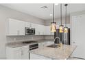 Modern kitchen featuring stainless steel appliances, granite countertops, white cabinetry, and pendant lighting at 356 Free Fall Ave, North Las Vegas, NV 89084