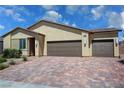 Single-story home featuring three car garage and brick driveway, with desert landscaping at 5528 Eleganza Ave, Pahrump, NV 89061