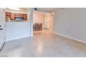 An empty living room with tile flooring, leading into a dining area and kitchen with dark wood cabinets at 7885 W Flamingo Rd # 1016, Las Vegas, NV 89147