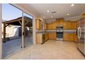 Well-lit kitchen features stainless appliances and wood cabinets, with an adjacent covered patio visible through sliding glass doors at 9678 Swaying Elms Ct, Las Vegas, NV 89147