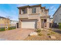 Two-story stucco home with stone accents, desert landscaping, and a brick paver driveway at 1338 Ossa St, Henderson, NV 89052