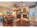 Cozy living room with hardwood floors, a fireplace, and large windows with plantation shutters at 2375 Malaga Peak St, Las Vegas, NV 89135