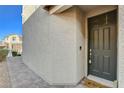 Close-up of the dark front door with modern hardware and a textured exterior wall at 4115 Spring Storm Ave, North Las Vegas, NV 89081