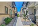 Between townhomes with a gray walkway lined with rock landscaping and green bushes at 4640 Flower Moon Ave # 102, North Las Vegas, NV 89084