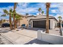 Charming home with desert landscaping, black garage door, and driveway leading to the garage at 6505 Moon Roses Ct, Las Vegas, NV 89108