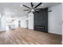 Open-concept living room with fireplace, modern ceiling fan, and hardwood floors leading to the kitchen at 6505 Moon Roses Ct, Las Vegas, NV 89108