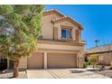 Two-story tan home featuring a two car garage and lush front yard tree at 74 Harbor Coast St, Las Vegas, NV 89148