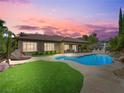 Beautiful backyard with a pool, lush lawn, lounge furniture, and an outdoor dining area under sunset skies at 11504 White Cliffs Ave, Las Vegas, NV 89138