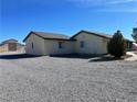 Side view of home with an outbuilding, gravel yard, and neutral stucco perfect for desert living at 1681 Appaloosa Ln, Pahrump, NV 89060