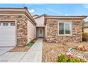 Close-up of a home's facade featuring stone accents, a front door with an oval glass pane, and desert landscaping at 2535 Jada Dr, Henderson, NV 89044