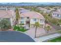 Aerial view of a luxury home in a desert community showing landscaping, a paver driveway, and mountain views at 11002 Inverlochy Ct, Las Vegas, NV 89141
