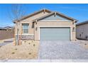Charming single-story home with a desert-landscaped front yard and gray brick driveway under a clear blue sky at 2404 Elmont Ave, North Las Vegas, NV 89086