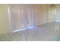 Living room featuring white tile flooring, vertical blinds, and a mirrored wall with chandelier at 3435 Villa Knolls South Dr, Las Vegas, NV 89120