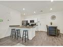 Eat-in kitchen features wood floors, white cabinets, granite countertops, stainless steel appliances, recessed lighting, and breakfast bar seating at 527 Clearsable Ave, Henderson, NV 89044