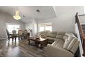 Open living space with wood floors, large sectional sofa and adjacent dining area under a chandelier at 2108 Running River Rd, Henderson, NV 89074