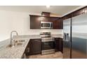 Modern kitchen featuring granite countertops, stainless steel appliances, and dark wood cabinetry at 2813 Riverside Gold Ct, North Las Vegas, NV 89086