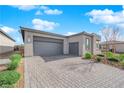 A contemporary home featuring a three-car garage and paved driveway in a desert landscape at 5095 E Long Leaf Ct, Pahrump, NV 89061