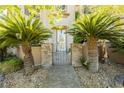 The front entrance features custom stone pillars with palm trees and a beautiful wrought iron gate at 7427 Tomahawk Bend Ave, Las Vegas, NV 89113