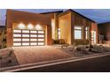 Contemporary home exterior featuring a stylish garage with translucent doors, modern landscaping, and a brick driveway at 10739 Agate Cliffs Ave, Las Vegas, NV 89135