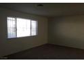 A bright living room features a window and neutral carpeting at 146 Greenbriar Townhouse Way, Las Vegas, NV 89121