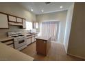 Bright kitchen featuring an island, tan tile flooring, plenty of cabinets, and a sliding glass door at 2100 Fred Brown Dr, Las Vegas, NV 89106