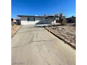 View of a single-story home with a concrete driveway leading to a white house and a leafless tree at 2564 San Marcos St, Las Vegas, NV 89115