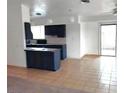 View of the kitchen with a tile floor, tile backsplash, dark blue cabinets, and a breakfast bar at 4508 W San Miguel Ave, North Las Vegas, NV 89032