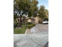 Single-story home featuring a well-maintained lawn, mature trees, and a paved driveway at 4738 Laurel Canyon St, Las Vegas, NV 89129