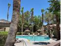 Community pool surrounded by lounge chairs and lush tropical landscaping at 5250 S Rainbow Blvd # 1010, Las Vegas, NV 89118