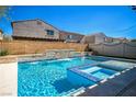 Relaxing backyard pool with a waterfall feature and integrated jacuzzi, surrounded by tasteful landscaping at 5628 Ridgeland St, North Las Vegas, NV 89031
