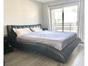 Modern bedroom featuring a large bed, sliding glass door, wood floors, and neutral wall color at 6250 W Flamingo Rd # 103, Las Vegas, NV 89103