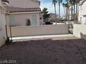 Desert rock landscaped backyard with a white wall and a metal gate at 70 Belle Essence Ave, Las Vegas, NV 89123