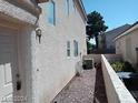 Beige stucco home with a white door, rock landscaping and an air conditioning unit at 70 Belle Essence Ave, Las Vegas, NV 89123