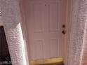 Close up of a light pink front door with gold hardware and stucco walls at 70 Belle Essence Ave, Las Vegas, NV 89123