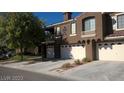 Modern townhome showcasing multi-car garage with a desert landscape and private balcony at 7290 Sheared Cliff Ln # 102, Las Vegas, NV 89149