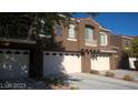 Modern townhome showcasing multi-car garage with a desert landscape and private balcony at 7290 Sheared Cliff Ln # 102, Las Vegas, NV 89149
