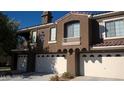Modern townhome showcasing multi-car garage with a desert landscape and private balcony at 7290 Sheared Cliff Ln # 102, Las Vegas, NV 89149