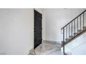 Bright foyer featuring sleek black front door, marble tile flooring, and carpeted staircase at 8469 Sewards Bluff Ave, Las Vegas, NV 89129