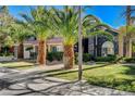 Charming front yard with mature palm trees and lush landscaping that perfectly complements the home's unique architectural features at 1859 Woodhaven Dr, Henderson, NV 89074
