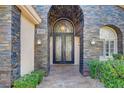 Elegant front entrance featuring an arched stone facade, a decorative iron door, and manicured landscaping for enhanced curb appeal at 1859 Woodhaven Dr, Henderson, NV 89074