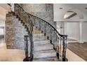 Grand staircase with iron railings and stone wall, complemented by wood floors and elegant columns in a bright, open foyer at 1859 Woodhaven Dr, Henderson, NV 89074